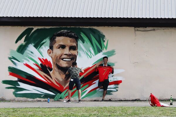 Болельщики рисуют граффити с изображением игрока сборной Португалии Криштиану Роналду
