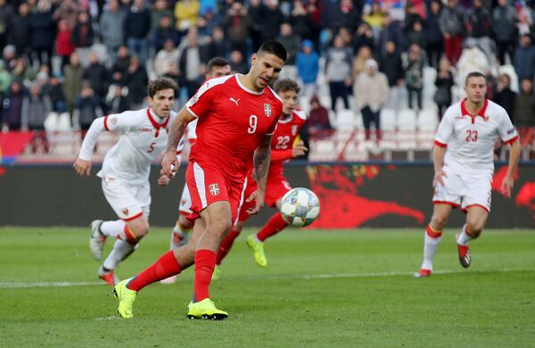 Форвард сборной Сербии Александар Митрович забивает мяч в ворота черногорцев