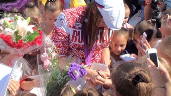 Окруженная юными гимнастками чемпионка Донскова ставит автографы на руках