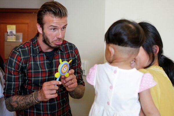 Экс-полузащитник сборной Англии по футболу Девид Бекхэм во время визита в больницу в китайском городе Ханчжоу играет с ребенком, страдающим врожденным пороком сердца