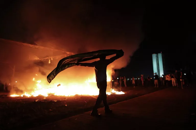 Демонстрант держит файер в знак протеста против повышения цен на проведение Кубка Конфедераций по футболу, а также против политики президента государства Дилмы Русеф. Демонстрант держит файер в знак протеста против повышения цен на проведение Кубка Конфедераций по футболу, а также против политики президента государства Дилмы Русеф.