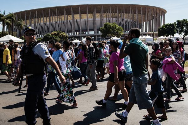 Демонстранты проходят мимо стадиона Манэ Гарринчи, одного из шести стадионов, принимающих Кубок Конфедераций по футболу