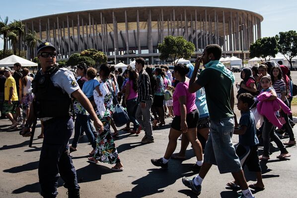 Демонстранты проходят мимо стадиона Манэ Гарринчи, одного из шести стадионов, принимающих Кубок Конфедераций по футболу