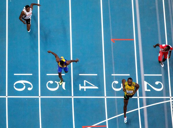 Ямайский спортсмен Усэйн Болт (второй справа) финиширует в забеге на 100 м