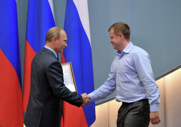 Президент России Владимир Путин (справа) вручает благодарственную грамоту мастеру спорта международного класса Максиму Соловьеву