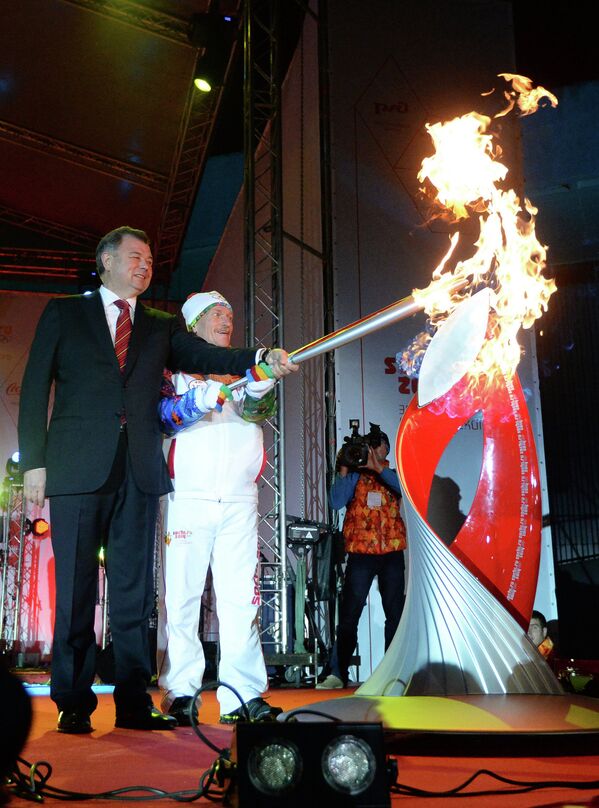 Правнук Константина Циолковского Сергей Самбуров (справа) зажигает чашу перед музеем космонавтики во время Эстафеты Олимпийского огня в Калуге