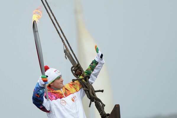 Факелоносец плывет на ладье по Оке во время эстафеты Олимпийского огня в городе Муром