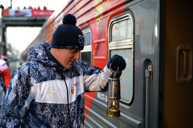 Хранитель огня заходит в железнодорожный вагон с лампадой олимпийского огня