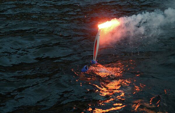 Спасатель Байкальского поисково-спасательного отряда МЧС России Николай Рыбаченко погружается в воду с факелом во время эстафеты олимпийского огня на озере Байкал