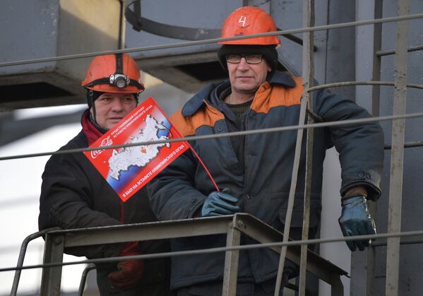 Рабочие наблюдают за эстафетой Олимпийского огня в Иркутске.