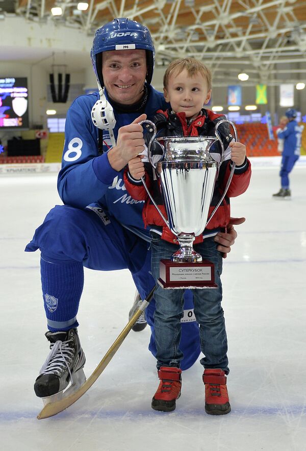 Игрок Динамо (Москва) Евгений Иванушкин с сыном держат кубок после окончания матча Суперкубка России по хоккею с мячом