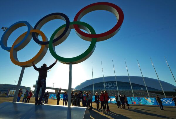 Мужчина фотографируется с олимпийскими кольцами в Олимпийском парке в Сочи