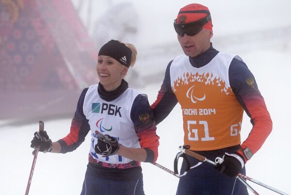 Михалина Лысова (Россия) и ведущий Алексей Иванов на финише гонки на средней дистанции в классе B 1-3 (слабовидящие) среди женщин