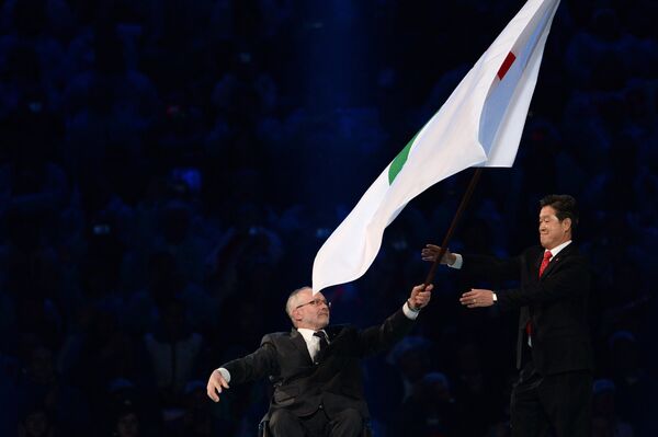 Президент Международного паралимпийского комитета (МПК) Филип Крейвен (слева) передает Паралимпийский флаг мэру города Пхенчхана Ли Сок Рэ на церемонии закрытия XI зимних Паралимпийских игр в Сочи