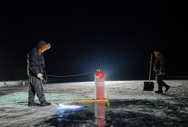 Рабочие обжигают лед озера Байкал ночью перед матчем-акцией Ночной Хоккейной Лиги Байкал – территория НХЛ