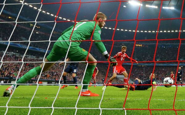 Полузащитник Баварии Томас Мюллер (в центре) забивает мяч в ворота голкипера Манчестер Юнайтед Давида де Хеа