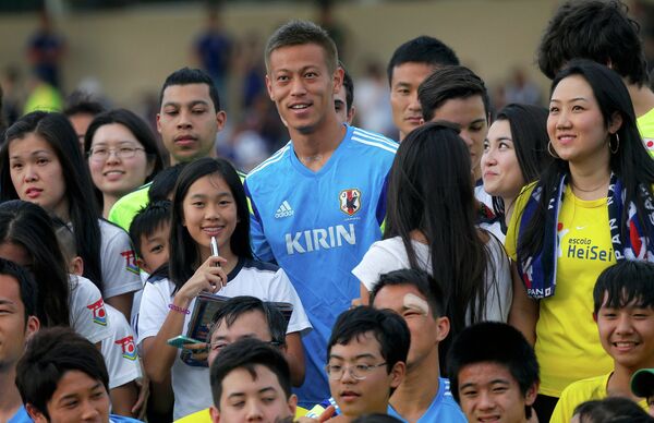 Полузащитник сборной Японии Кэйсукэ Хонда фотографируется вместе с фанатами