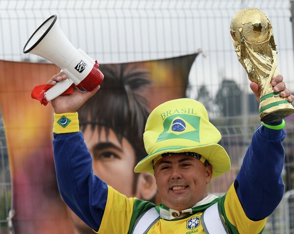 Болельщик сборной Бразилии с макетом Кубка мира у стадиона Арена Коринтианс в Сан-Паулу