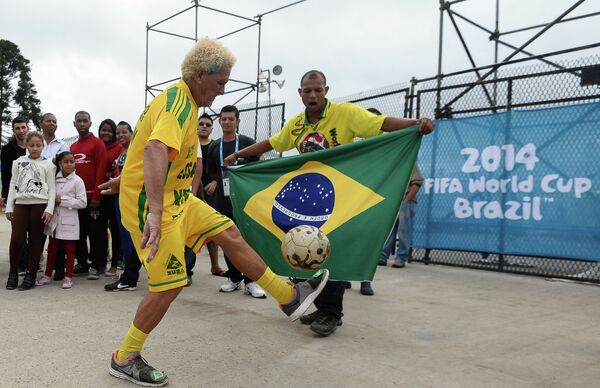 Болельщик сборной Бразилии демонстрирует мастерство обращения с футбольным мячем у стадиона Арена Коринтианс в Сан-Паулу