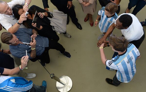 Британский футболист Дэвид Бэкхем фотографирует своих детей с бразильским футболистом Пеле перед финальным матчем чемпионата мира по футболу 2014 Германия - Аргентина.
