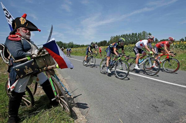Болельщик наблюдает за группой велогонщиков во время тринадцатого этапа Тур де Франс между городами Сент-Этьен и Шанрус