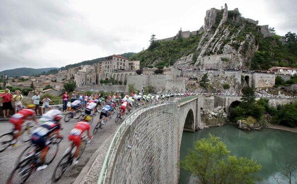 Группа велогонщиков преодолевает мост на участке пятнадцатого этапа Тур де Франс между городами Таллар и Ним