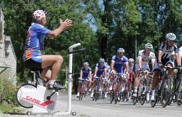 Болельщик на велотренажере приветствует гонщиков на участке одиннадцатого этапа Тур де Франс