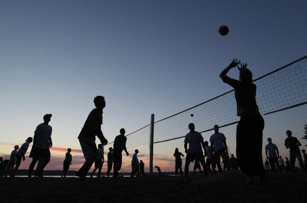 Молодые спортсмены играют на закате в волейбол