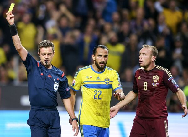 Главный судья матча показывает желтую карточку игроку сборной Швеции Эркау Зенгину (в центре)