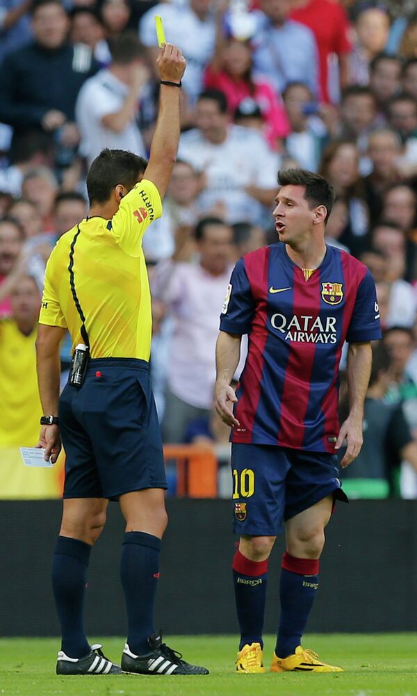 Судья матча Реал - Барселона показывает желтую карточку нападающему каталонской команды Лионелю Месси