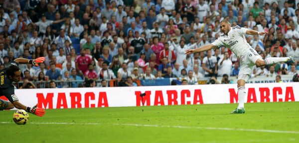 Нападающий мадридского Реала Карим Бензема (справа) забивает мяч в ворота голкипера Барселоны Клаудио Браво