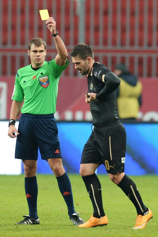 Судья показывает желтую карточку форварду ФК Рубин Марко Ливайя (справа)