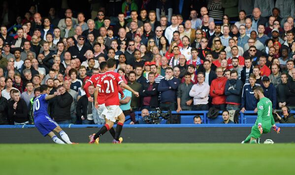 Полузащитник Челси Эден Азар забивает мяч в ворота голкипера Манчестер Юнайтед Давида Де Хеа (справа)