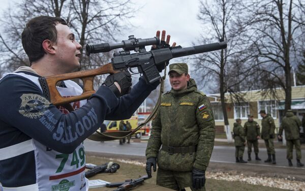 Участник массового военно-спортивного мероприятия Гонка героев осматривает снайперскую винтовку на военном полигоне Алабино Таманской мотострелковой дивизии в Московской области