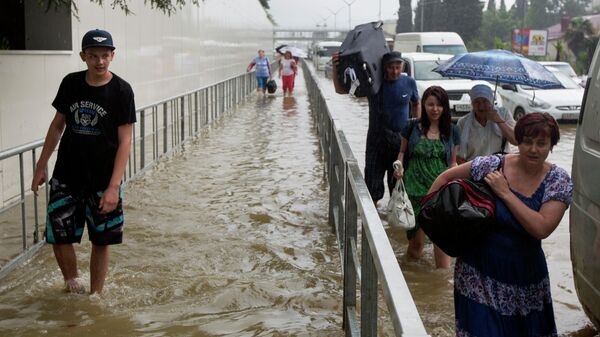 Люди на одной из улиц Сочи, затопленных в результате проливных дождей