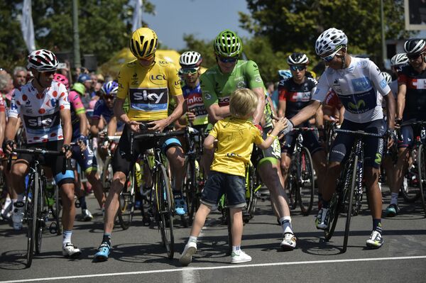 Ребенок жмет руки велосипедистам на старте очередного этапа Тур де Франс - 2015