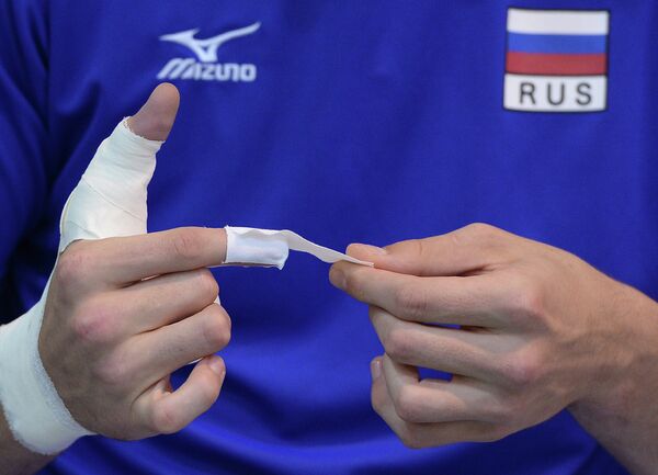 Блокирующий мужской сборной команды России по волейболу Илья Власов бинтует пальцы на тренировке