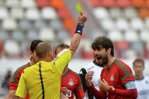 Защитник Локомотива Ведран Чорлука (справа) получает желтую карточку от главного судьи Сергея Иванова