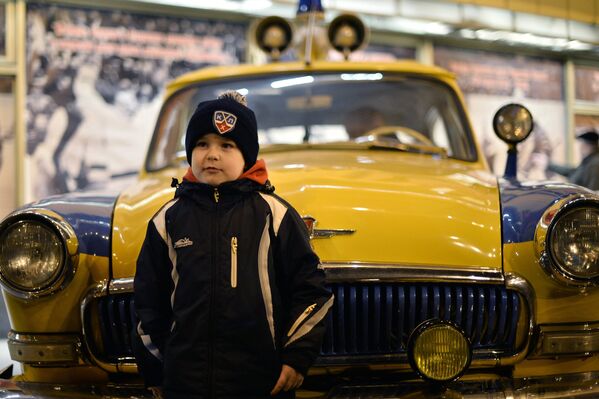 Юный болельщик позирует фотографируется у милицейского автомобиля ГАЗ-21 Волга