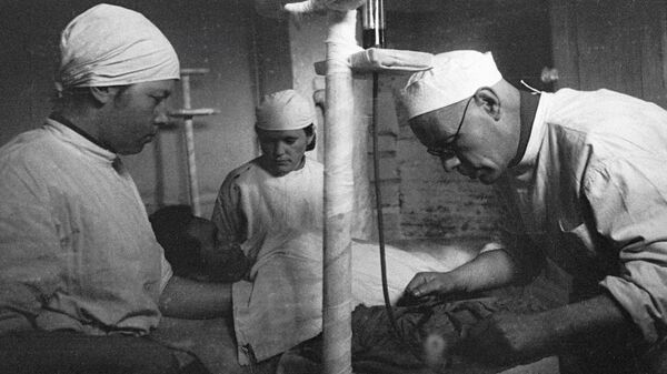 Врачи и медсестра военного госпиталя за работой. Один из врачей ставит капельницу раненному. Сентябрь 1941 года 